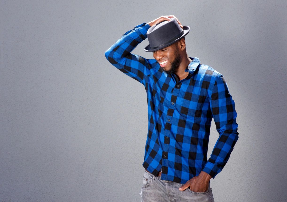 Man in blue plaid shirt and hat smiling.